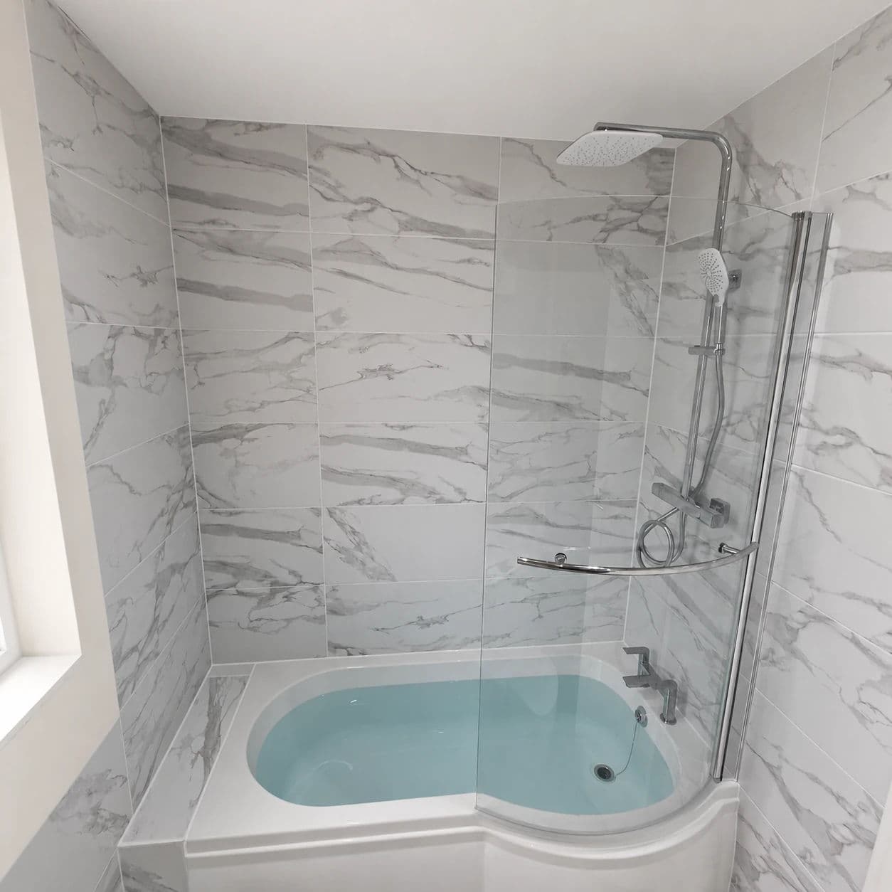Middlesbrough Bathroom Installation and Refurbishment with P-Shaped Bath and Rainfall Shower in Middlesbrough — after completion. Services: Bathroom Installation, Bathroom Refurbishment, Bathroom Tiling, Bathtub Installation, Flooring, Plumbing, Lighting, Shower Installation, Bathroom Renovation.